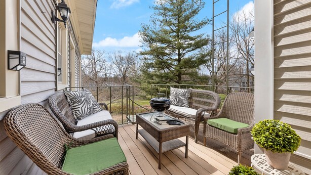 A covered outdoor deck with wicker furniture, a glass-top table, and a potted plant. - - Beautiful Condo - King Bed - Free Waffle Breakfast - (Geneva)