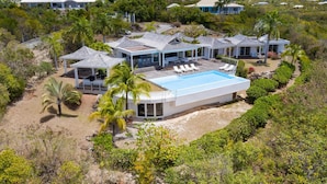 Et moderne resort med flere villaer, en fælles pool og frodig tropisk vegetation.