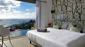 A bedroom with a large bed, a view of the sea, and a modern design.