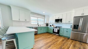 Une cuisine moderne avec des armoires de couleur turquoise, un réfrigérateur en acier inoxydable et un plancher en bois.