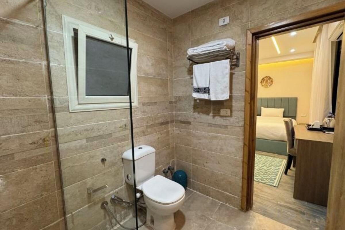 Een badkamer met een douchecabine van glas, een toilet en een handdoekrek.