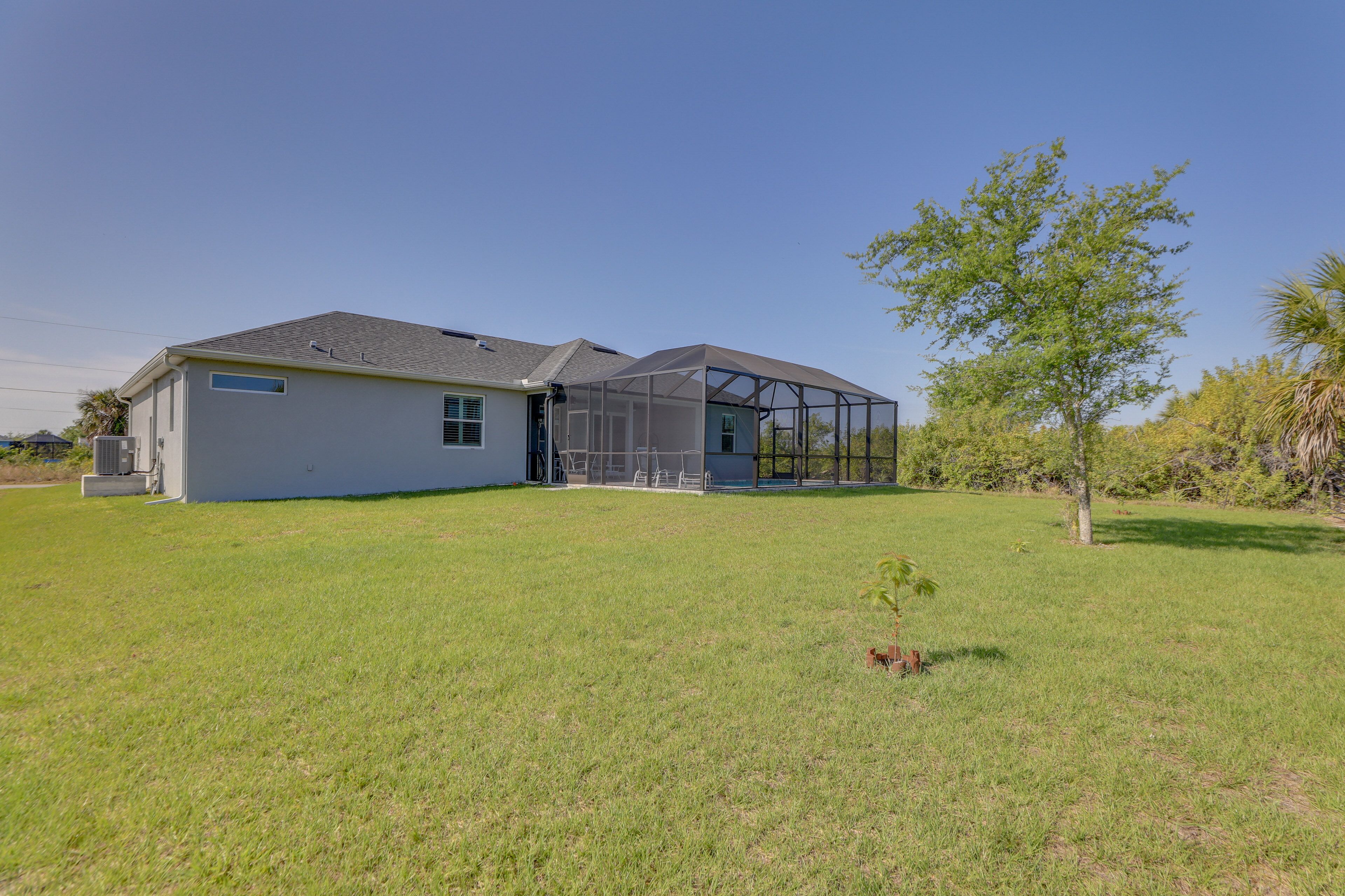 A modern house with a large glass extension, a well-maintained lawn, and a small tree.