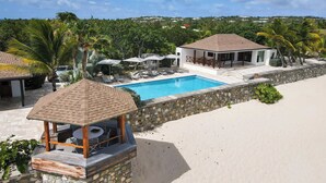 Ein Poolbereich mit einer Steinmauer, Liegestühlen und Sonnenschirmen.