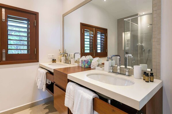 Un baño moderno con dos lavamanos, un espejo grande y armarios de madera.