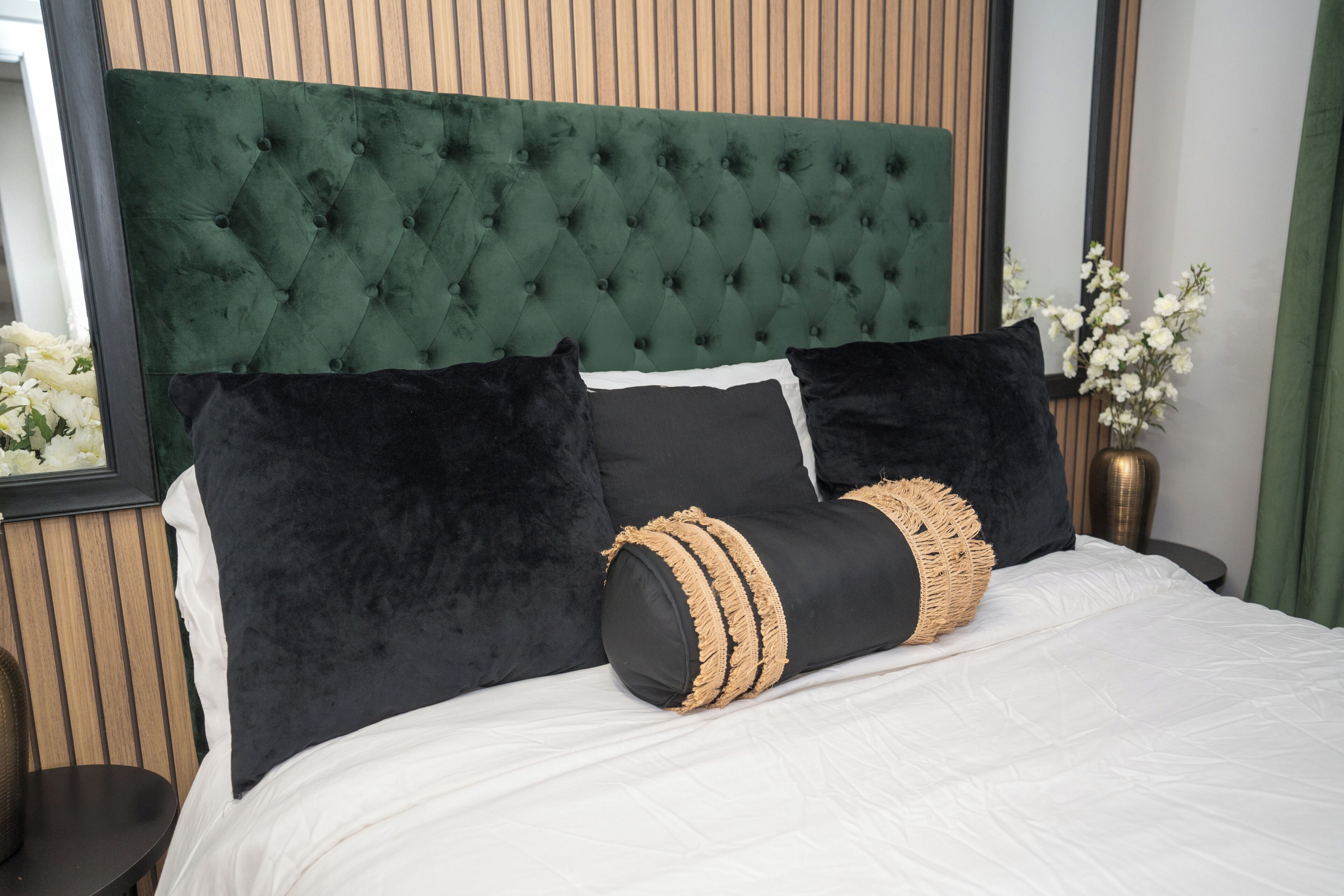 A bed with a tufted headboard, black and white bedding, and decorative pillows.
