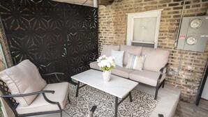 Un espacio al aire libre con sofás, sillas, una mesa y un jarrón decorativo.