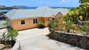 A two-story building with a stone retaining wall, a paved driveway, and a view of the ocean.