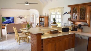 A spacious kitchen with wooden cabinets, a central island, and a dining area with chairs.