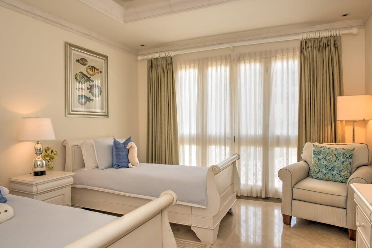 Habitación de hotel con dos camas, una silla, una lámpara y un cuadro en la pared.