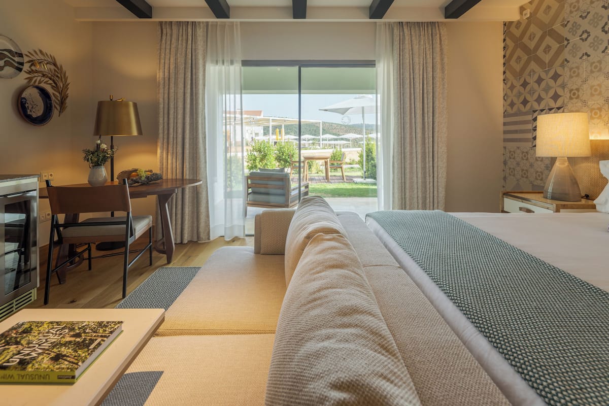 Une chambre d’hôtel équipée d’un lit, d’un bureau, d’une chaise, d’une lampe et offrant une vue sur l’extérieur.