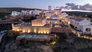A resort with multiple buildings, a swimming pool, and a mountainous backdrop.