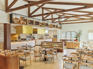A spacious restaurant with high ceilings, exposed wooden beams, and a variety of seating arrangements including tables and booths.