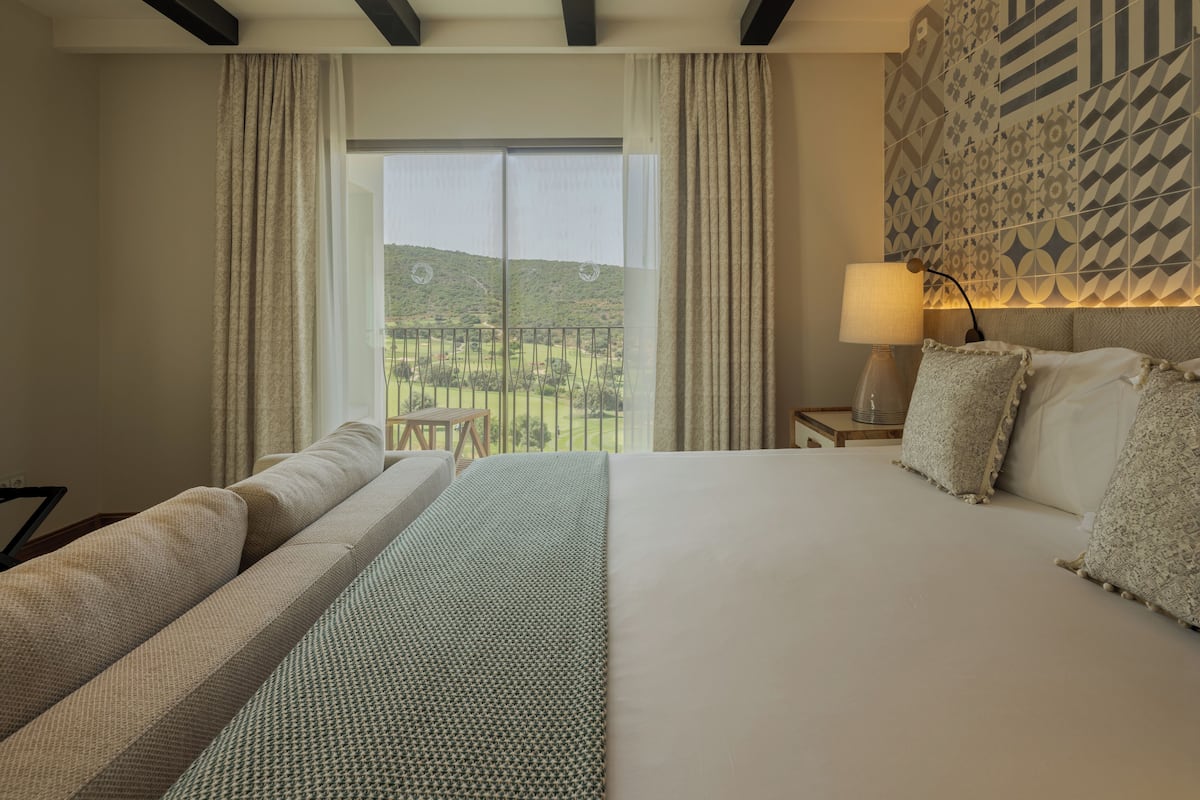 Une chambre d’hôtel avec un grand lit, une vue sur un terrain de golf et un mur décoré de motifs.