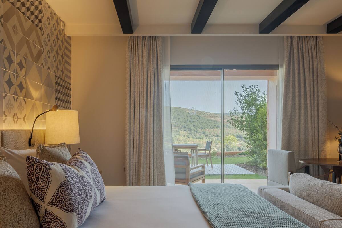 Une chambre d’hôtel avec un lit, un canapé, une table et une vue sur l’extérieur.
