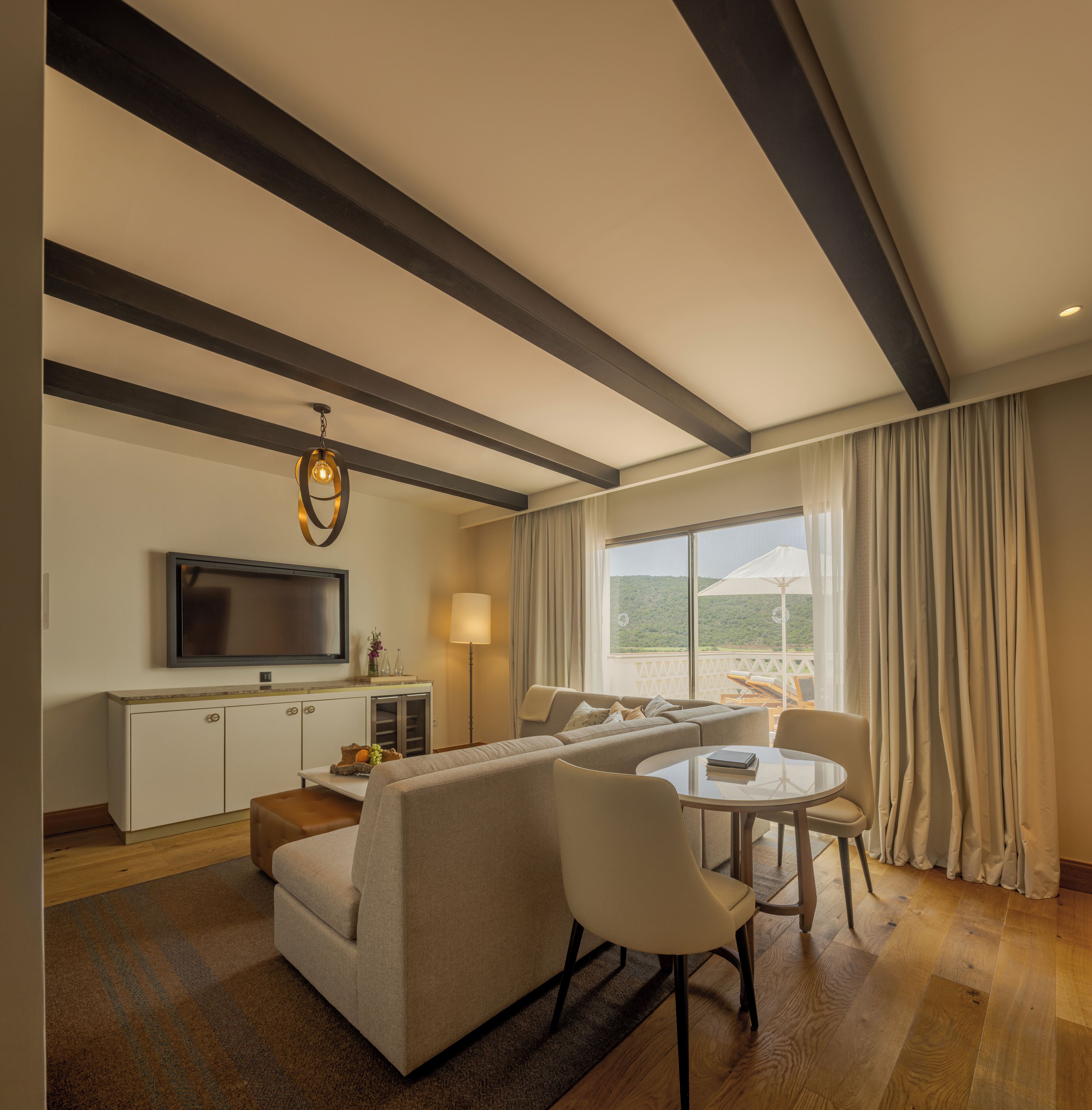 A modern living room with a sofa, chairs, a TV, and a dining area.