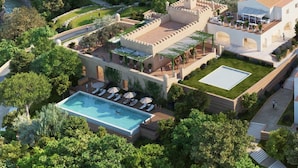 An aerial view of a resort with a swimming pool, outdoor seating, and lush greenery.