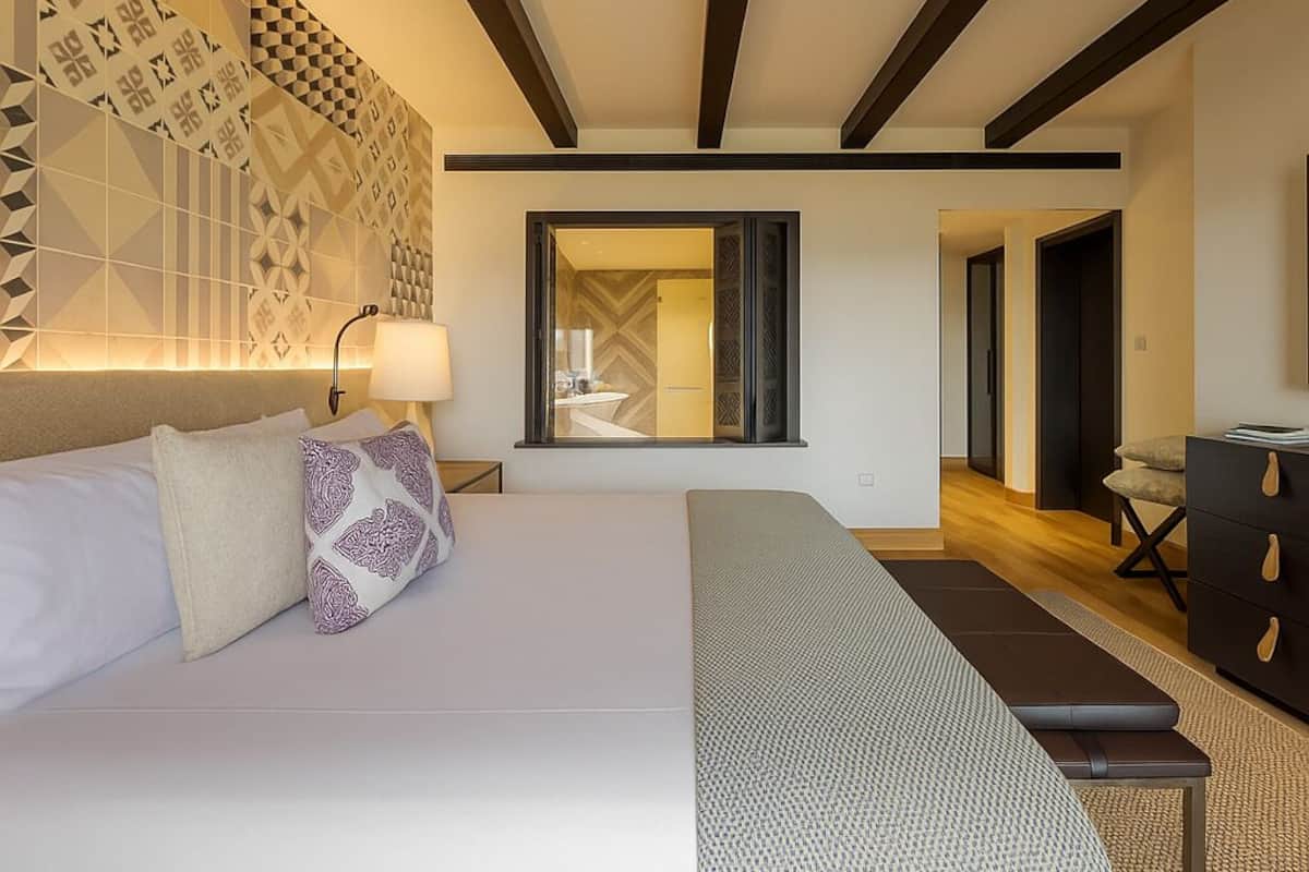 Une chambre d’hôtel moderne avec un grand lit, un banc, un bureau et une armoire.