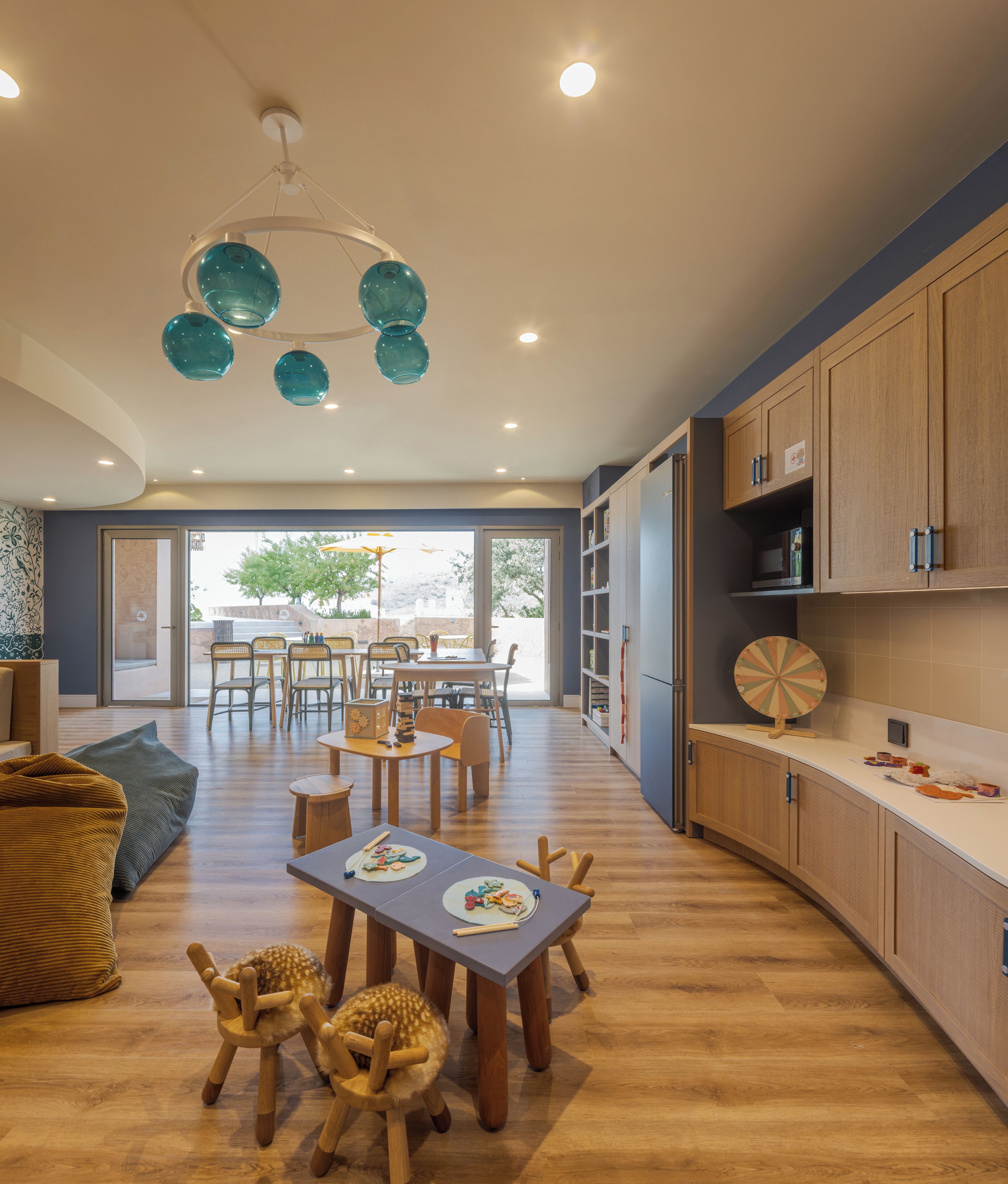 A modern kitchen with wooden cabinets, a dining area with a table and chairs, and a view of the outdoors.