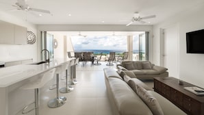 A modern kitchen with a bar area, a dining set, and a sofa. - 25 Westmoreland Hills | Modern Caribbean Villa with Spectacular Sunset Views (St James)