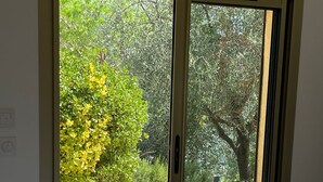 A room with a sliding glass door leading to an outdoor area with a gravel path and greenery. - Villa Sleeps 10, 4 Bedrooms, with Pool and Sea and Mountain View (Le Tignet)