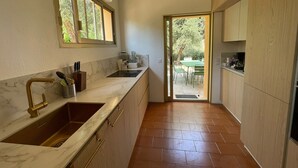A modern kitchen with a marble countertop, a sink, and a dining area visible through an open door. - Villa Sleeps 10, 4 Bedrooms, with Pool and Sea and Mountain View (Le Tignet)