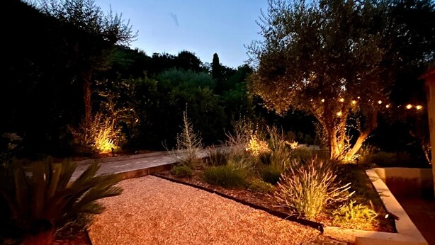 A garden pathway with mulch and plants, illuminated by string lights. - Villa Sleeps 10, 4 Bedrooms, with Pool and Sea and Mountain View (Le Tignet)