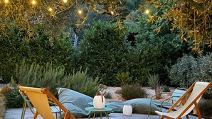 An outdoor seating area with wooden deck, cushioned chairs, and a small table. - Villa Sleeps 10, 4 Bedrooms, with Pool and Sea and Mountain View (Le Tignet)
