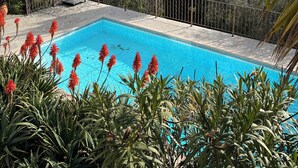A swimming pool with a view of a cityscape, surrounded by greenery and a metal fence. - Villa Sleeps 10, 4 Bedrooms, with Pool and Sea and Mountain View (Le Tignet)