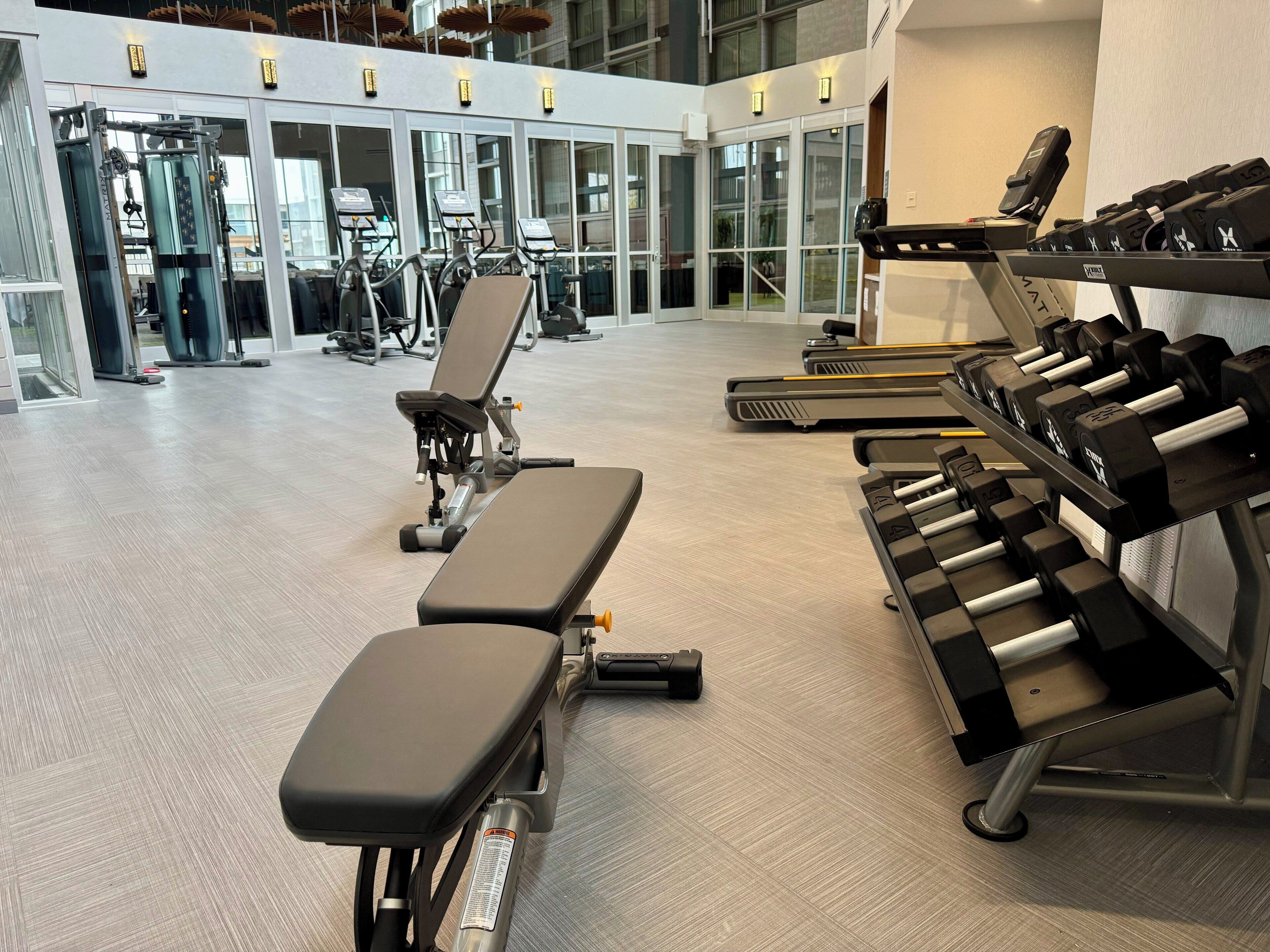A gym with exercise equipment, benches, and dumbbells.