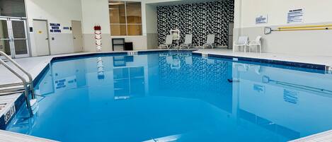 An indoor swimming pool with clear water, tiled walls, and a checkered pattern wall.