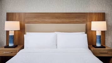 A hotel room with a wooden headboard, two bedside tables with lamps, and a bed with white linens.