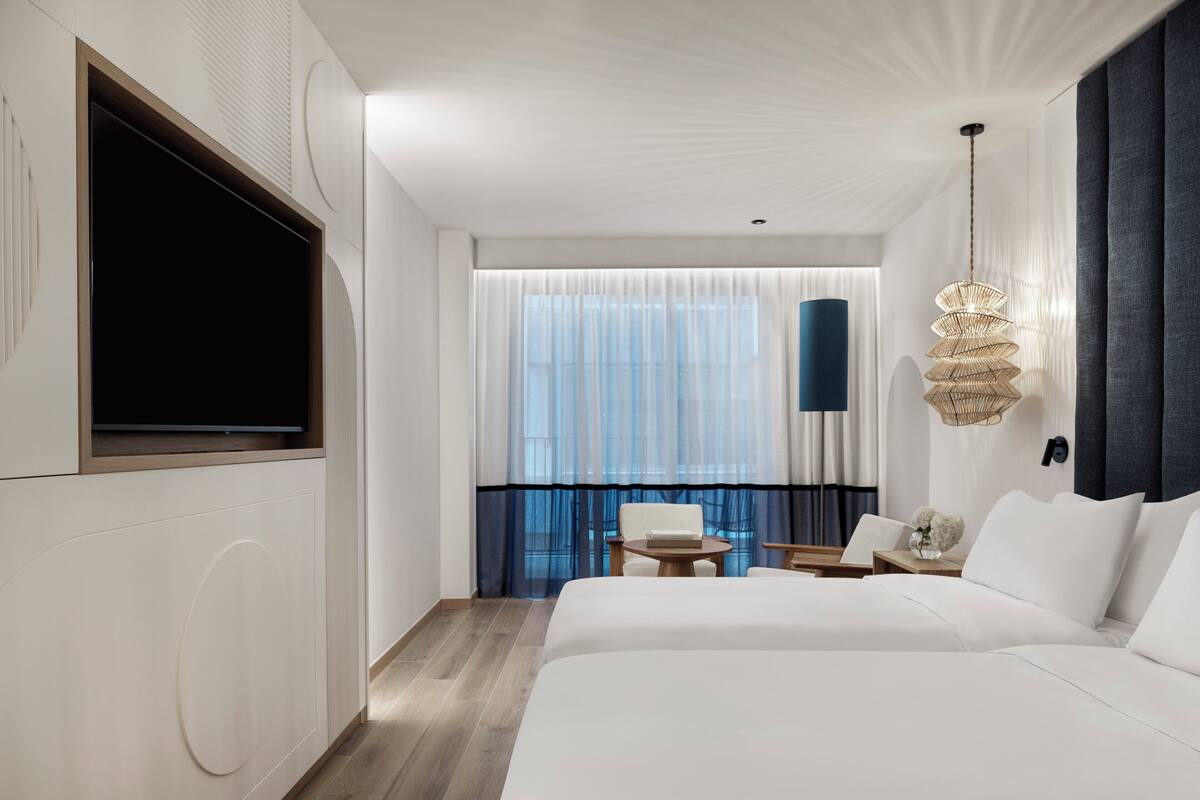 Ein Hotelzimmer mit einem großen Bett, einem Fernseher, einem Balkon mit Blick und einer hängenden Leuchte.