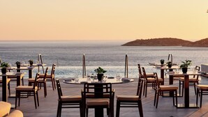 Un espace extérieur aménagé pour les repas, avec des tables et des chaises, offrant une vue sur la mer.