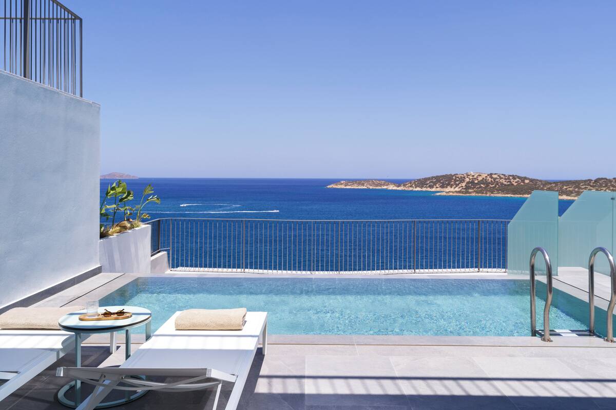 Ein Pool ohne Ende mit freiem Blick auf das Meer und eine entfernte Insel.