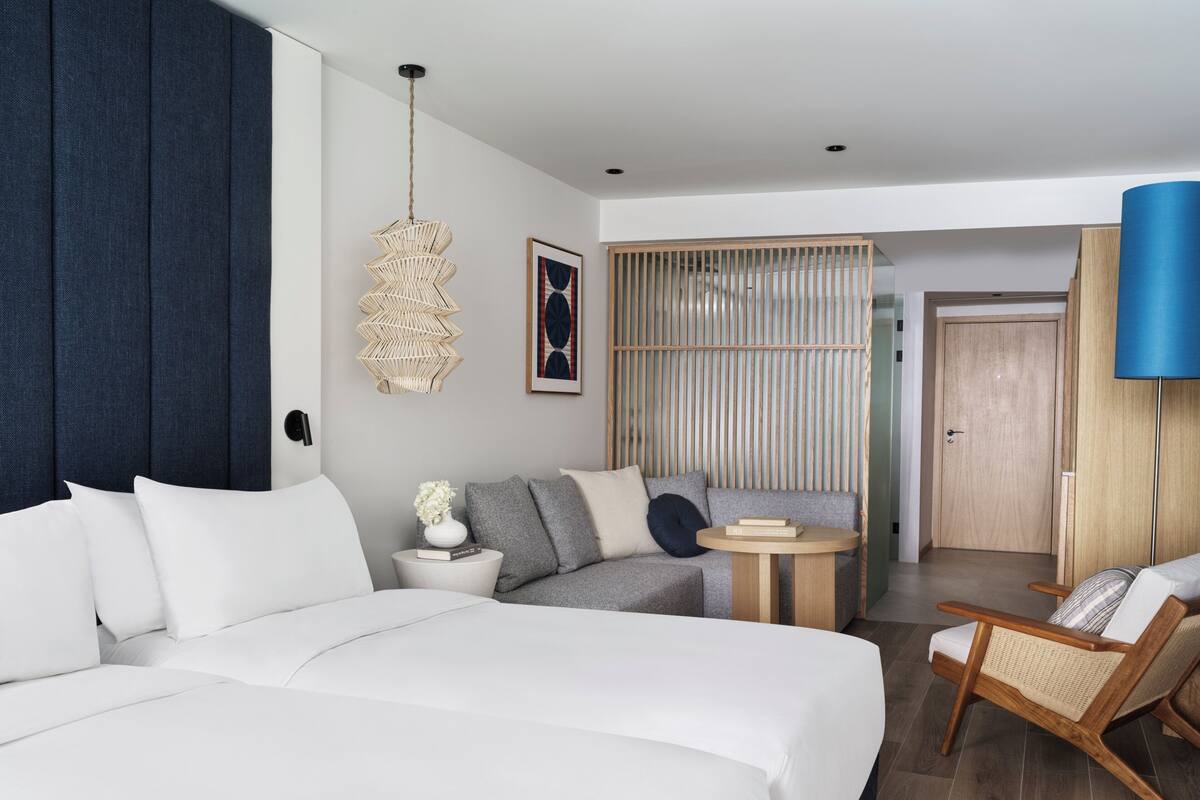 Ein modernes Hotelzimmer mit einem großen Bett, einer Couch, einem kleinen runden Tisch und einem Sessel.