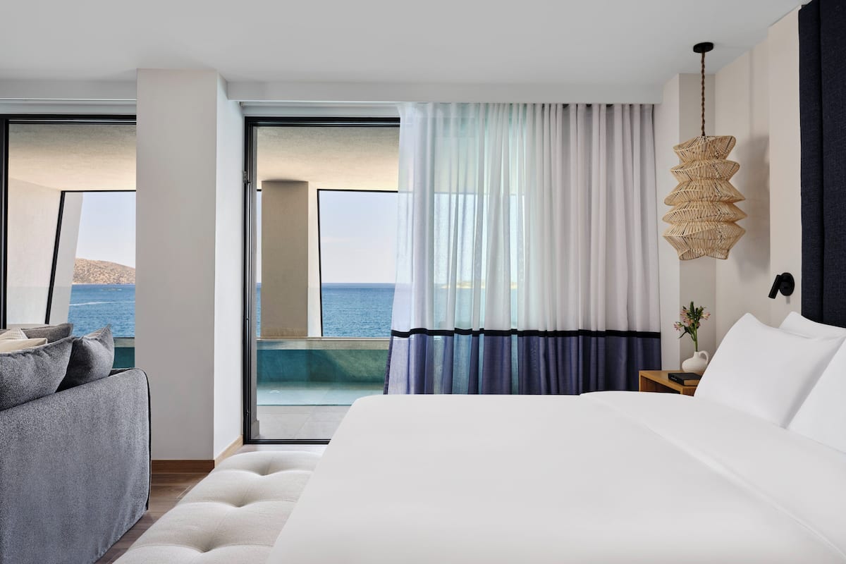 Ein modernes Hotelzimmer mit einem großen Bett, Meerblick und einem Balkon.