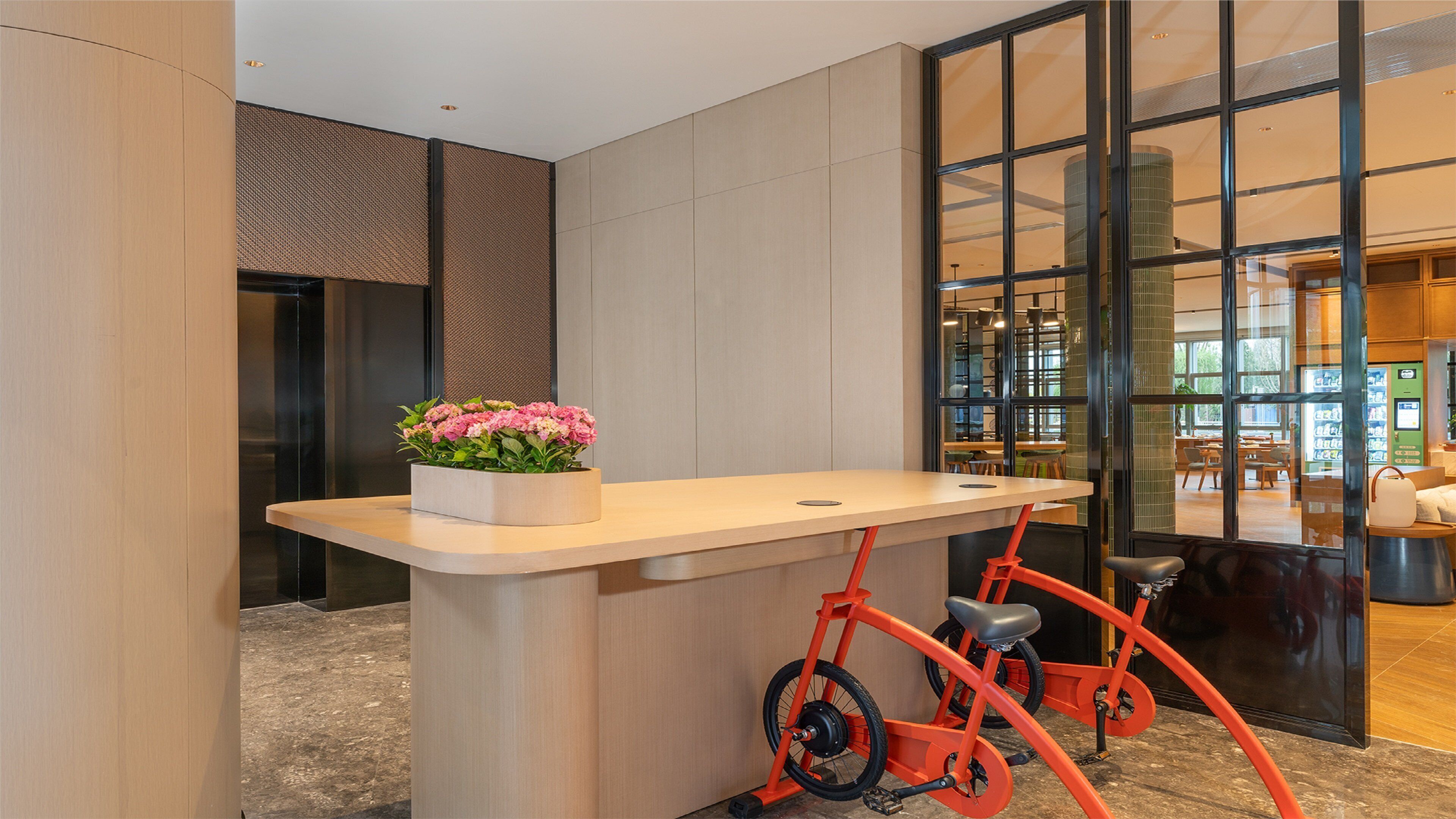Un comptoir d’accueil agrémenté d’une plante en pot, d’un vélo et offrant une vue sur l’espace intérieur.