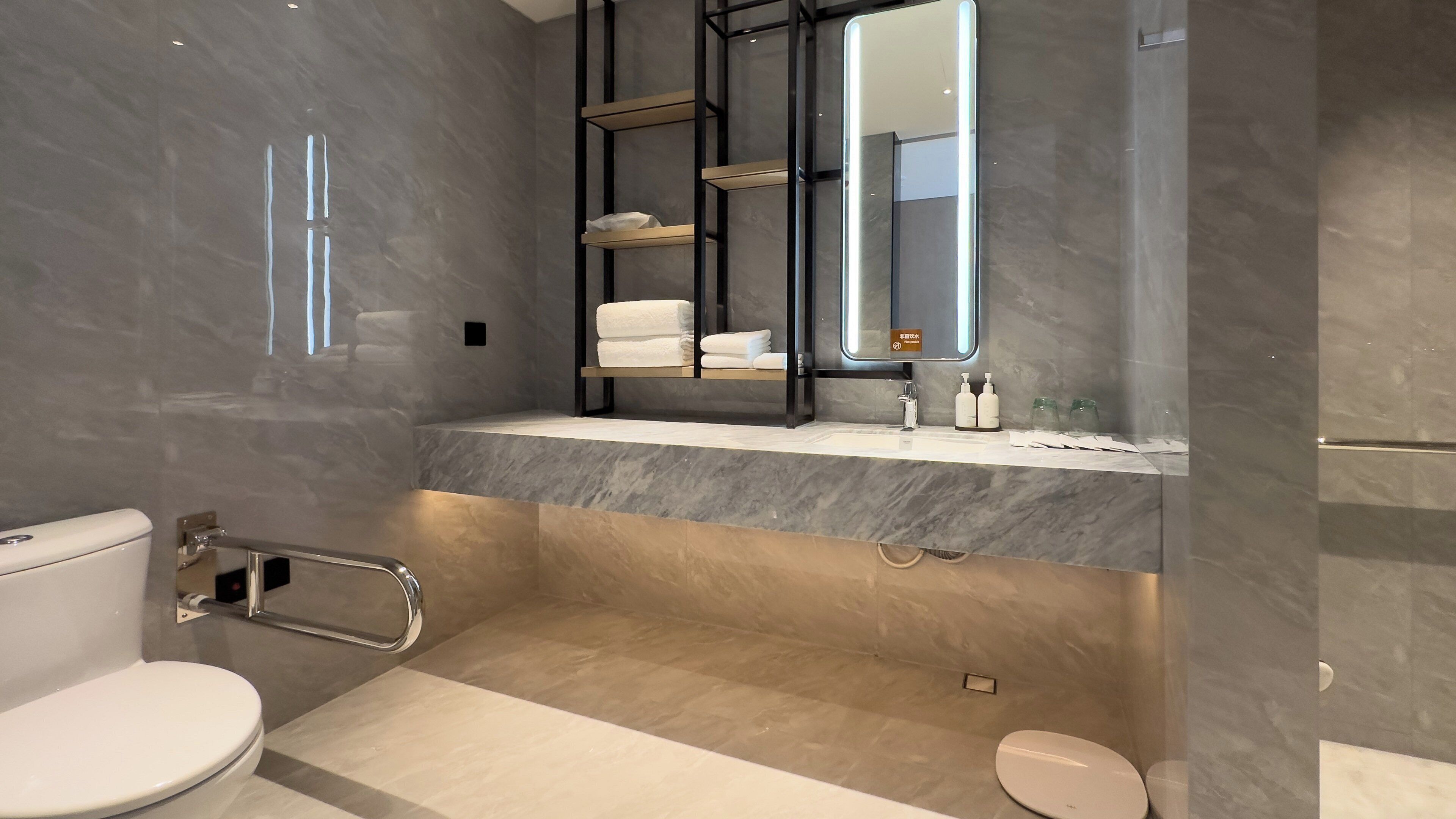 A modern bathroom with a marble vanity, a toilet, and a shower area.