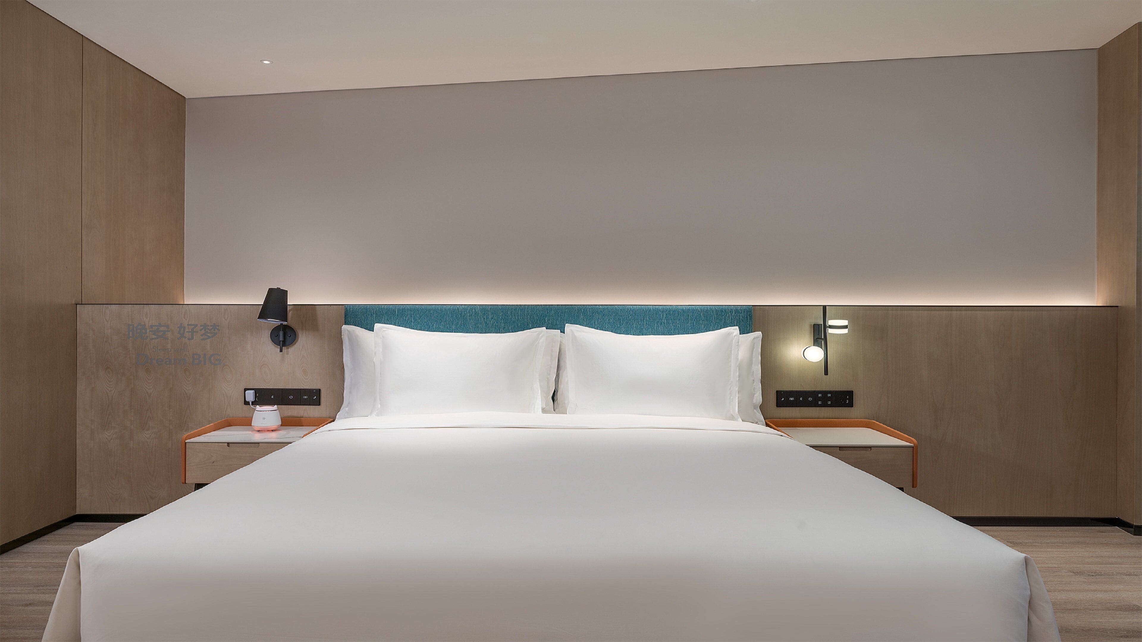 Habitación de hotel con una cama grande, dos mesitas de noche, un teléfono en la pared y un tocador con lámpara.