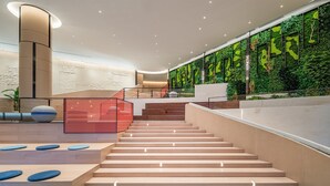 A modern interior with a staircase, wooden flooring, and a green wall with vertical gardens.