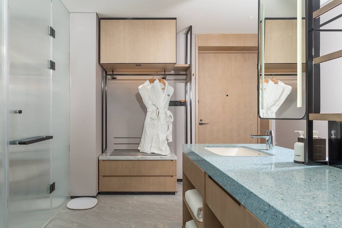 A modern bathroom with a glass shower enclosure, a wooden vanity with a sink, and a large mirror.