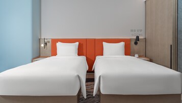 Habitación de hotel con dos camas individuales, una mesita de noche con lámpara y una obra de arte colgada en la pared.