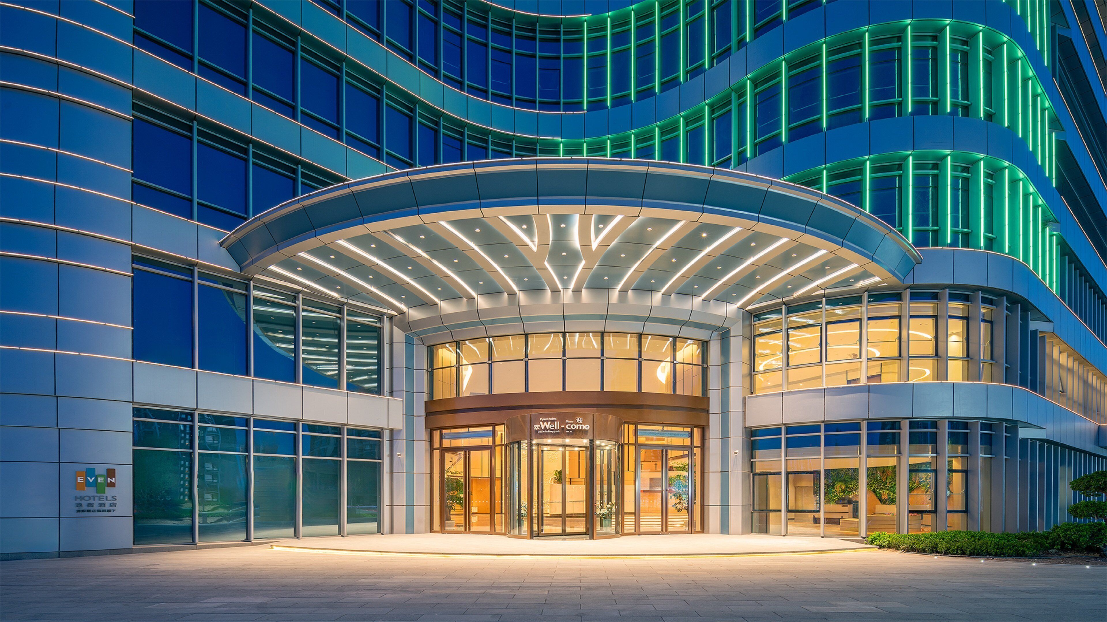 A modern hotel entrance with a curved glass facade and a well-lit entrance area.