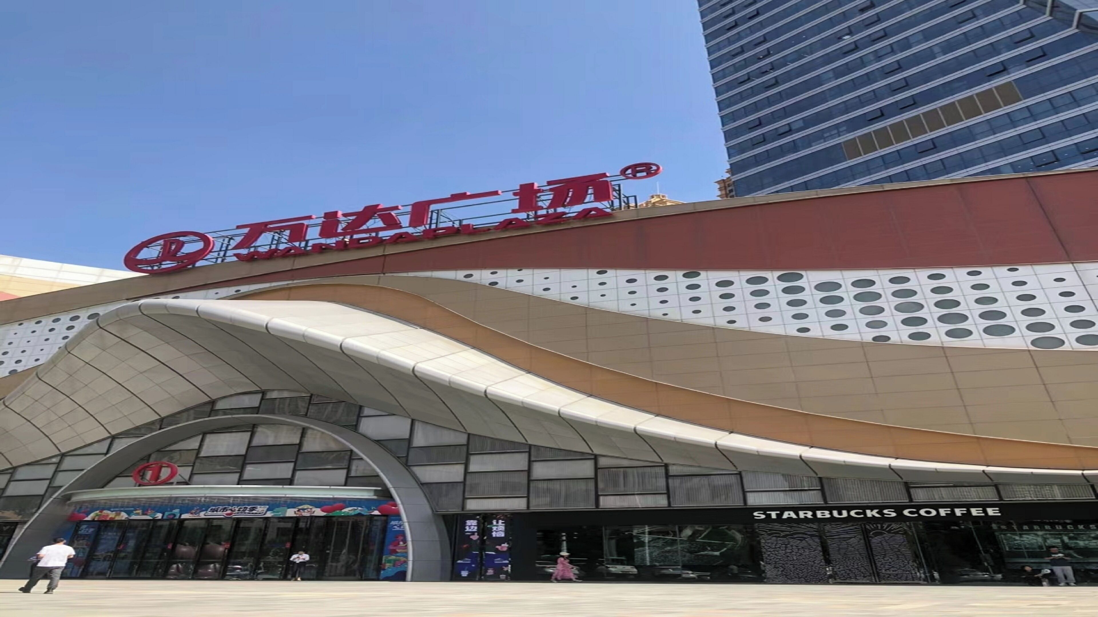 A modern building with a curved facade and a prominent red logo.