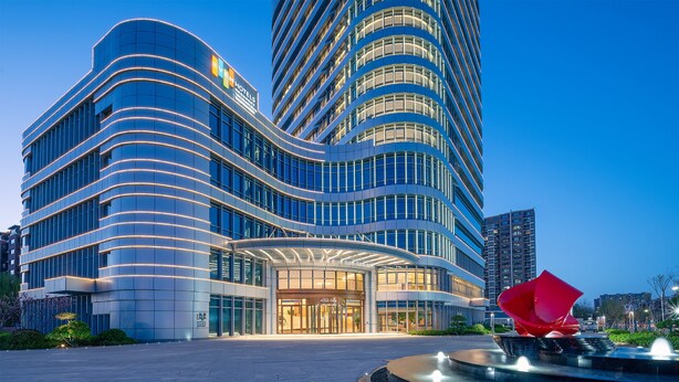 A modern hotel with a curved facade, large glass windows, and a prominent entrance.