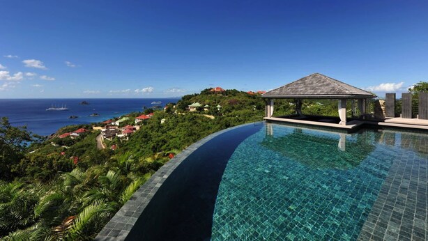 A clear blue sky, a swimming pool with a curved edge, and a gazebo structure. - Beautiful 3 bedroom villa located within minutes of the beach and surrounded by green gardens (Gustavia)