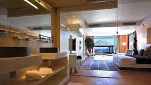 A modern hotel room with a large bed, a seating area with a view, and a bathroom with a large mirror and shelves. - Beautiful 3 bedroom villa located within minutes of the beach and surrounded by green gardens (Gustavia)