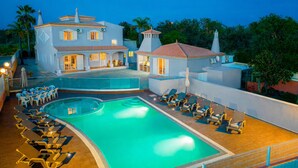 A large building with a swimming pool, lounge chairs, and a covered patio area. - Villa Dubai (Albufeira)