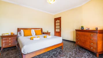 A hotel room with a bed, wooden nightstands, a dresser, and a door.