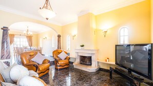 A spacious living room with a fireplace, leather armchairs, a sofa, and a television. - Villa Dubai (Albufeira)